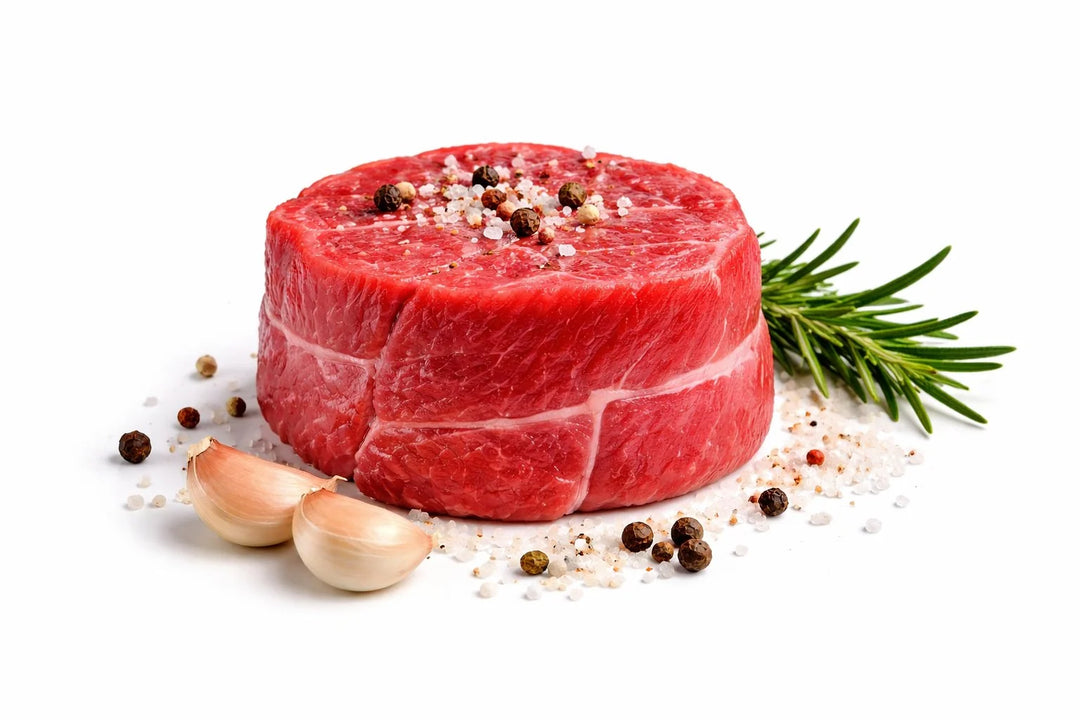Filetto di bovino fresco da 250 gr su sfondo bianco con sale grosso pepe in grani aglio e rosmarino