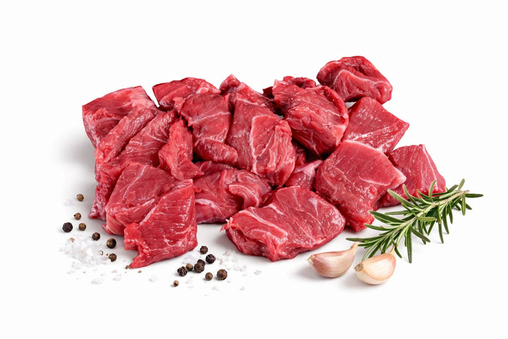 Spezzatino di Chianina fresco su sfondo bianco con sale grosso pepe in grani aglio e rosmarino